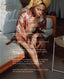 A woman in a bedroom setting wearing a rust-colored floral robe and a yellow headwrap, with text overlays detailing the benefits of Dead Sea salt, moisturizing butter, and lavender.