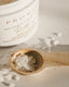 Jar of bath salts with a wooden spoon containing some of the salts on a light background