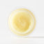 Close-up of a small container with yellowish cream on a white background